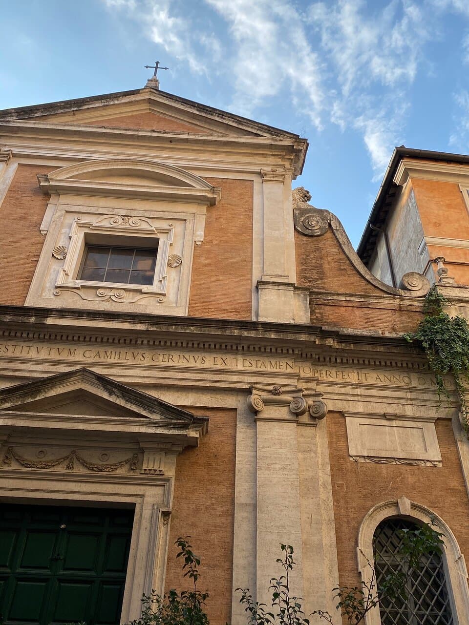 The second storey has a pair of Doric pilasters with derivative capitals, which support a triangular pediment with a blank tympanum. There is a central square window with a very wide frame embellished with curlicues and scallop shells, over which is a segmental pediment.