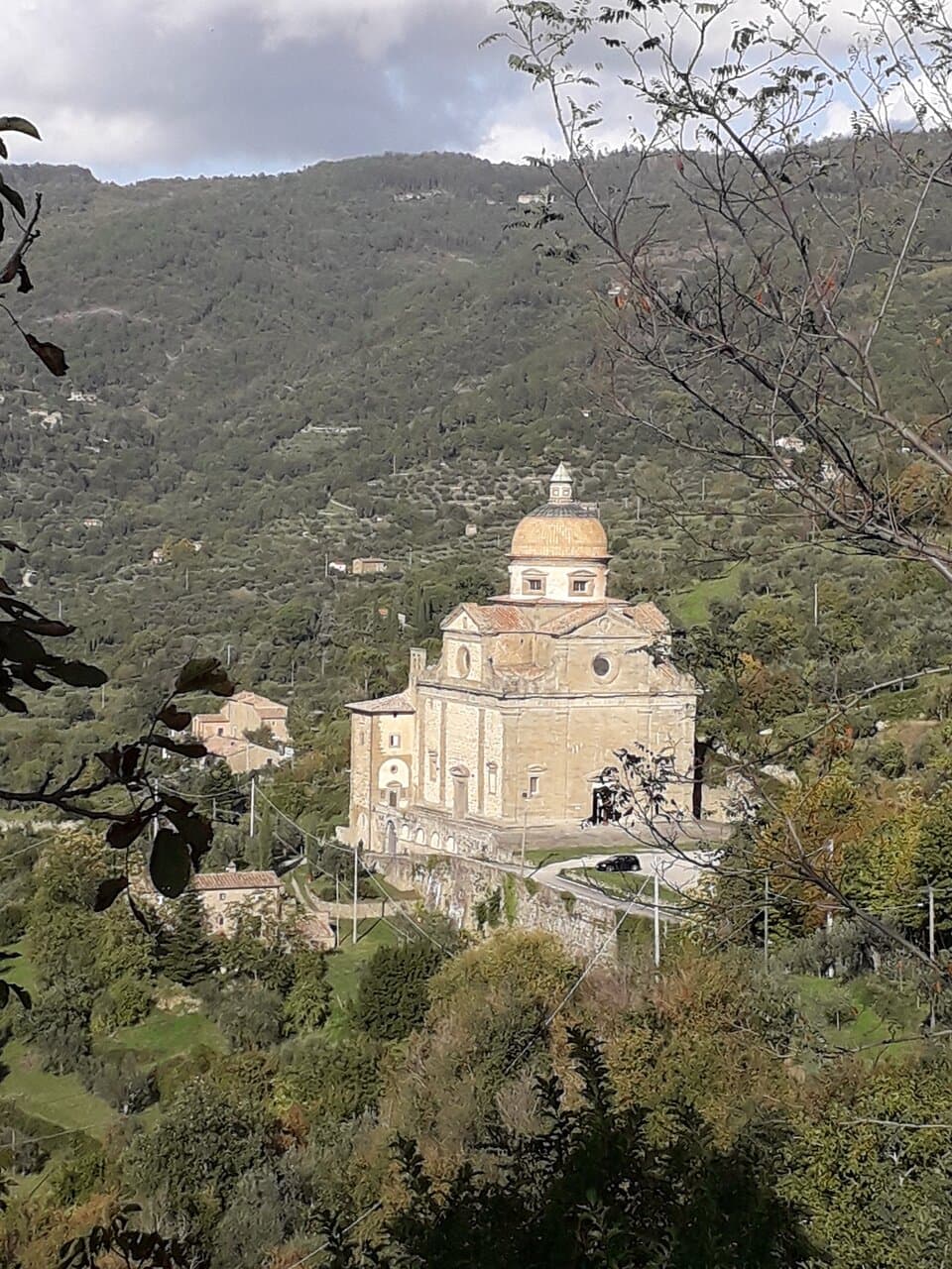 The church, scenically located in a frame of wooded hills, seen from the viewpoint of Piazza Mazzini.