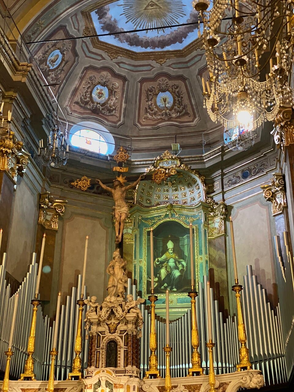 Central nave. On the main altar, the altarpiece is a large painting depicting St. Ambrose, the patron saint of Alassio, majestically seated on the bishop's chair, the work of an unknown Genoese painter of the seventeenth century.