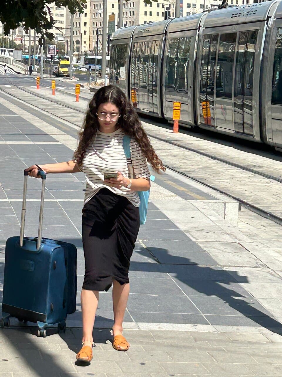 Walking with suitcase and focused on cellphone immediately after exiting the light rail