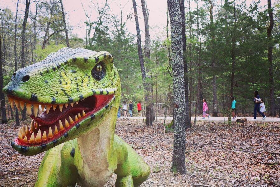 A Deinonychus on the Oaklawn Foundation DinoTrek at Mid-America Science Museum. Girls in the background from Girls in STEM workshop are on their way to plant a Gingko tree near the Brachiosaurus on the end of the DinoTrek.