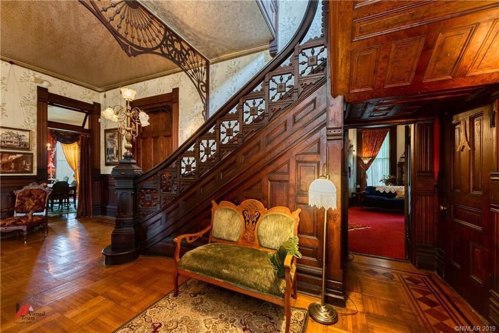 Side entrance door photo. Original flooring and  gingerbread on stair entrance