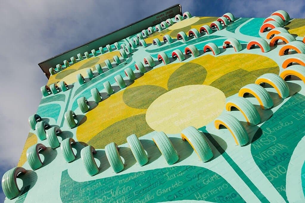 Se han pintado todos los apellidos de los vecinos, que lo han solicitad,o a modo de homenaje de este barrio obrero de Vitoria. Es un enorme papel pintado Vintage de los años 60-70 como los que colocaban ellos mismos, como podian, para decorar las paredes. Las ruedas simbolizan los largos trayectos que hacian para buscar trabajo a la España Industrial.