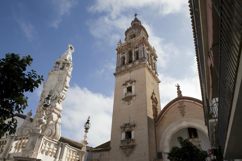 Fachada y torre. A la izquierda monumento a los patrones de Écija