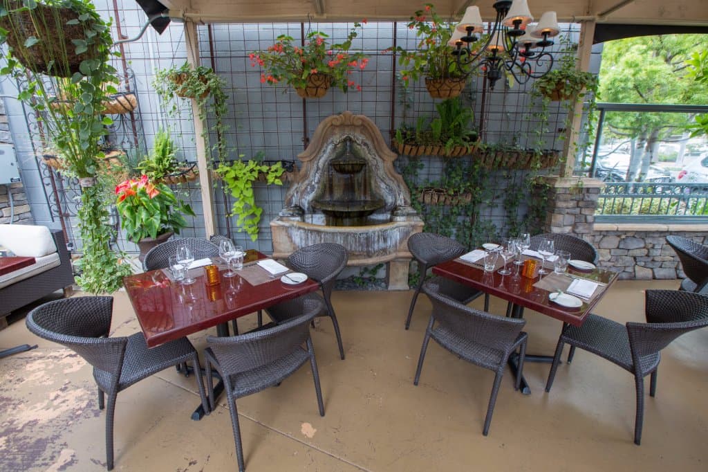 Beautiful outside patio with lush greenery, flowing water fountain, and outside heaters