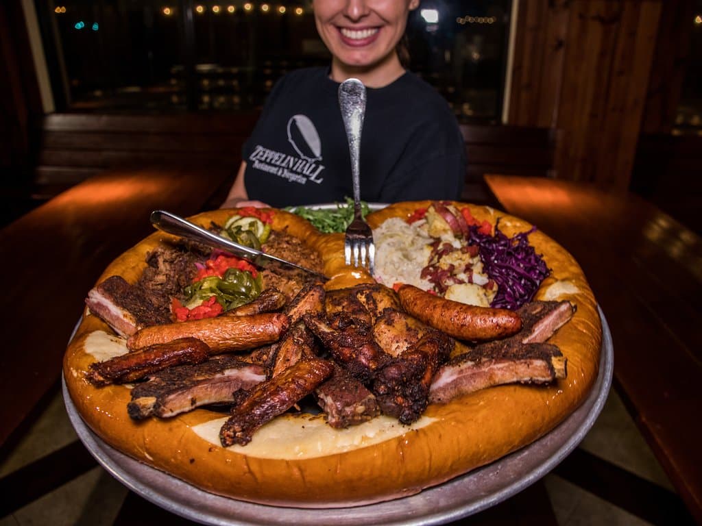 Ring of Fire! Great selection of pulled pork, chopped brisket, smoked chicken wings, St. Louis ribs, smoked chicken and Andouille sausage with pickles, jalapenos, pickles onions, sauerkraft, spicy red cabbage and German potato salad served in enormous pretzel