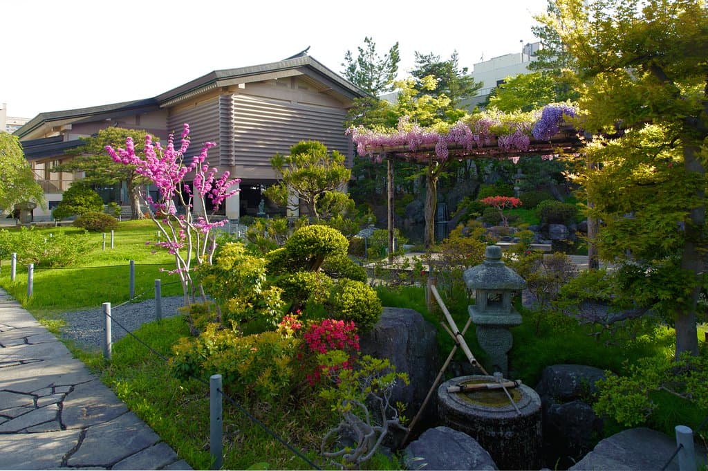 校倉造りを模した建物と、池泉回遊式の日本庭園。春。