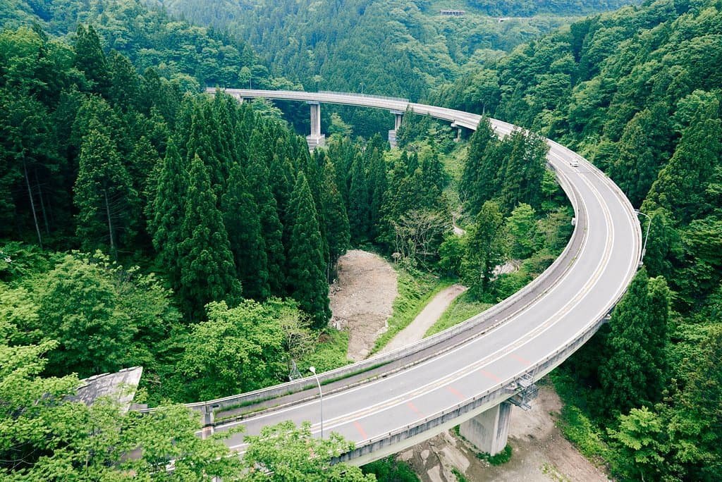 奥出雲おろちループは、広島県と島根県をつなぐ国道314号線の坂根～三井野原区間の高低差105mを一気に駆け上るために作られました。大小11の橋と3つのトンネルからなる日本最大規模の二重ループ方式道路です。名称の奥出雲おろちループは日本神話の「ヤマタノオロチ」より名づけられました。「道の駅奥出雲おろちループ」や「奥出雲鉄の彫刻美術館」が付近にあり、お食事や土産を購入する事ができます。