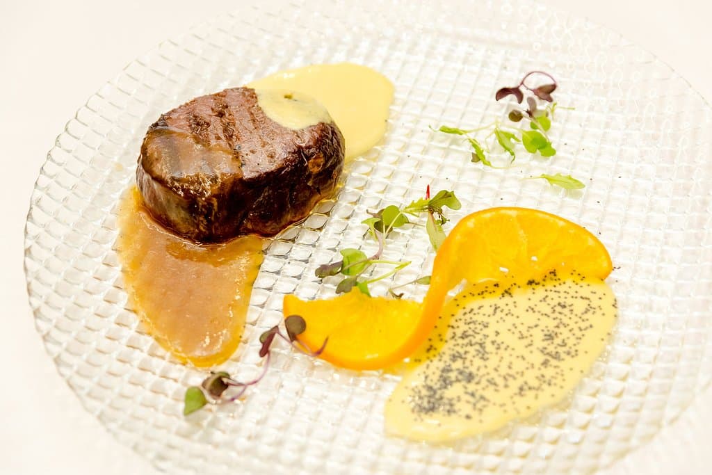 Medallón de ciervo a la brasa con salsa de la pasión
y reducción de naranja con puré de patatas al estilo emociones.