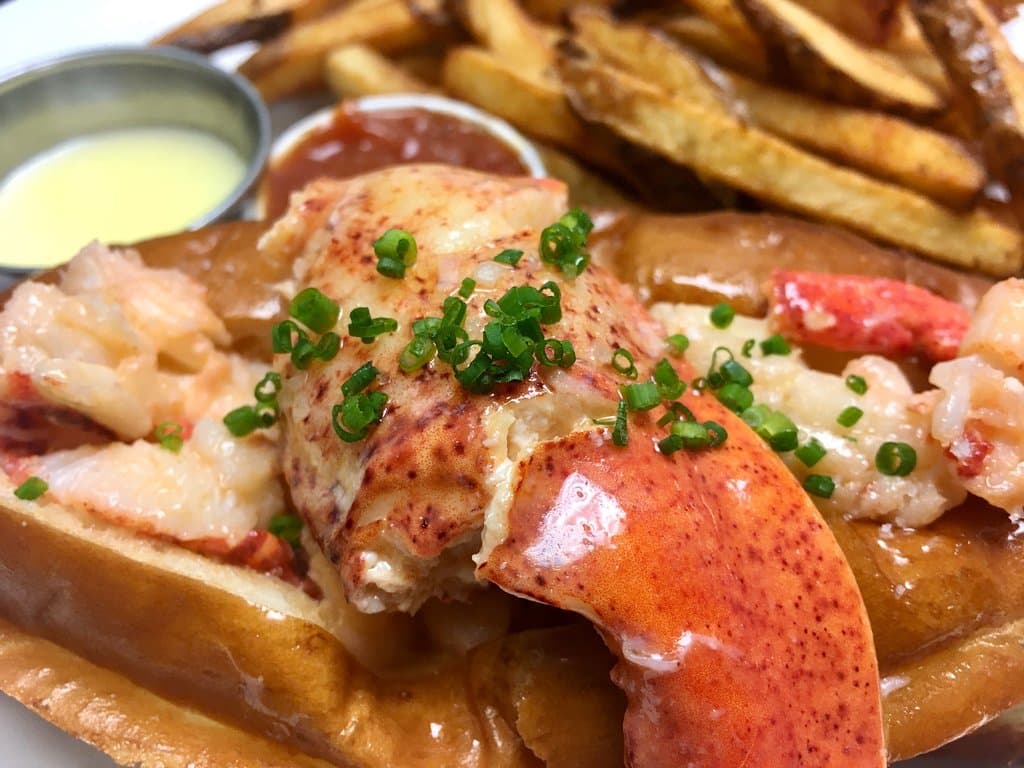 Hot butter poached New England lobster roll! Claw, tail, and knuckle on a griddled split top bun.