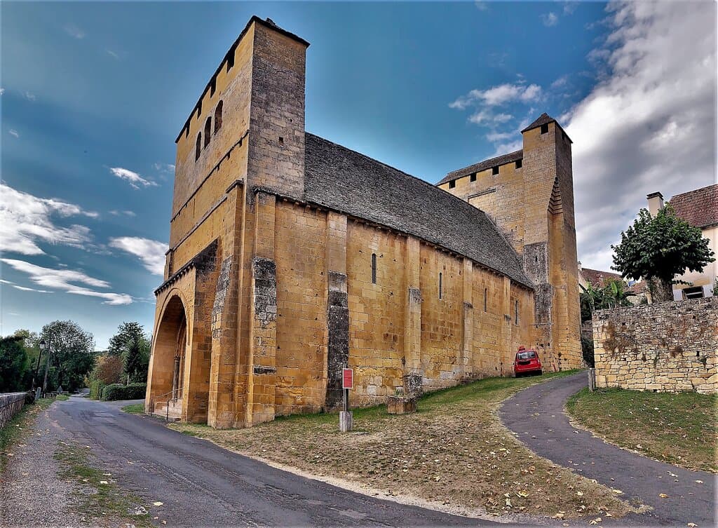 Une église sans clocher et sans croix, une église "fortement fortifiée". Elle a traversé trois conflits et y a survécu : la guerre de cent ans, les guerres de religions, et la fronde qui vit s'opposer vers 1652-1653 les villes de Sarlat à celles de périgueux et Bergerac.