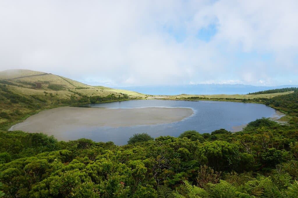 Lagoa do Caiado, com o mar e a Ilha de São Jorge no horizonte.