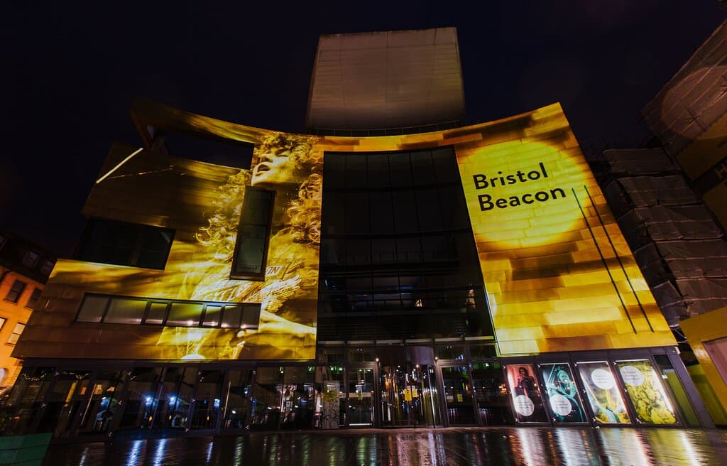 The iconic front of Bristol Beacon taken in September 2020 lit with projections created by Limbic Cinema of artists who have performed at the venue. Photo by Dominika Sheibinger.