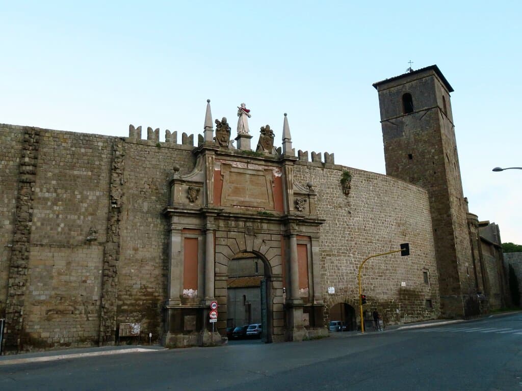 Porta Romana con alla sua dx il campanile della chiesa di San Sisto (di cui si intravede anche l'abside nelle mura), che era un precedente torre (e un tempo ne esisteva una analoga alla sx della porta)
