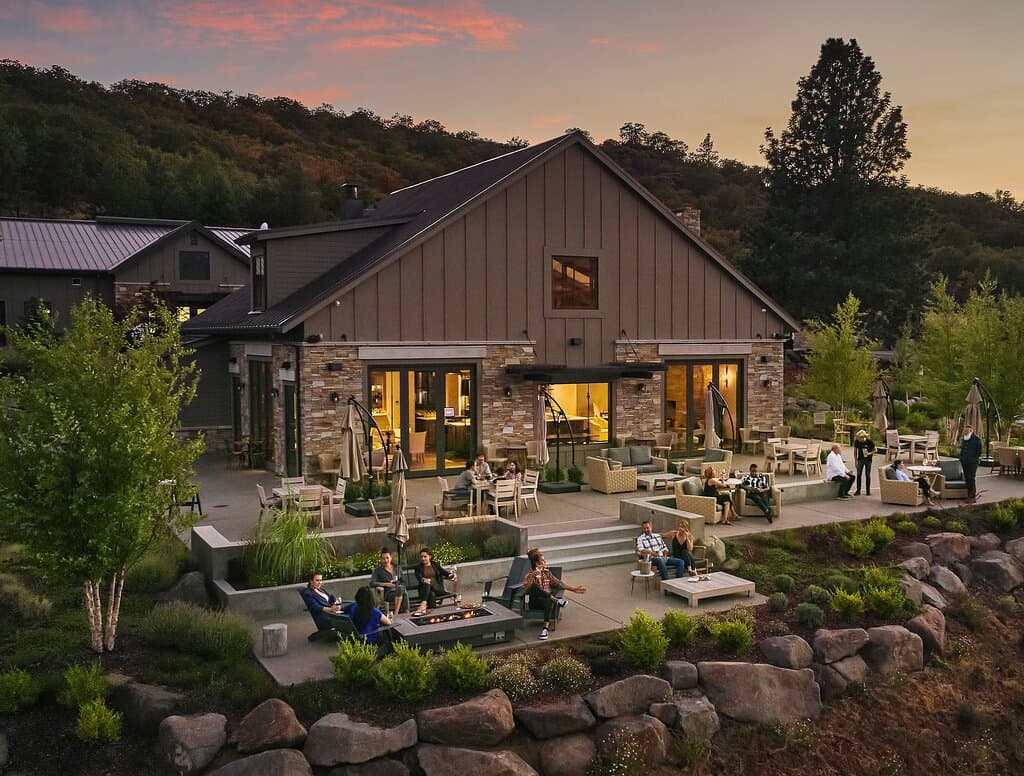 Sun sets over our tasting room patio while a few guests linger to enjoy the sunset and the warmth of the fireplace.