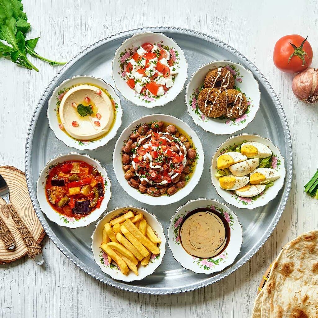 Egyptian Breakfast Tray
A tray that includes foul beans, falafel, boiled egg, musaqaa, fried potatoes, hummus, white cheese with tomato, black molasses with tahini and served with fresh tanoor bread.