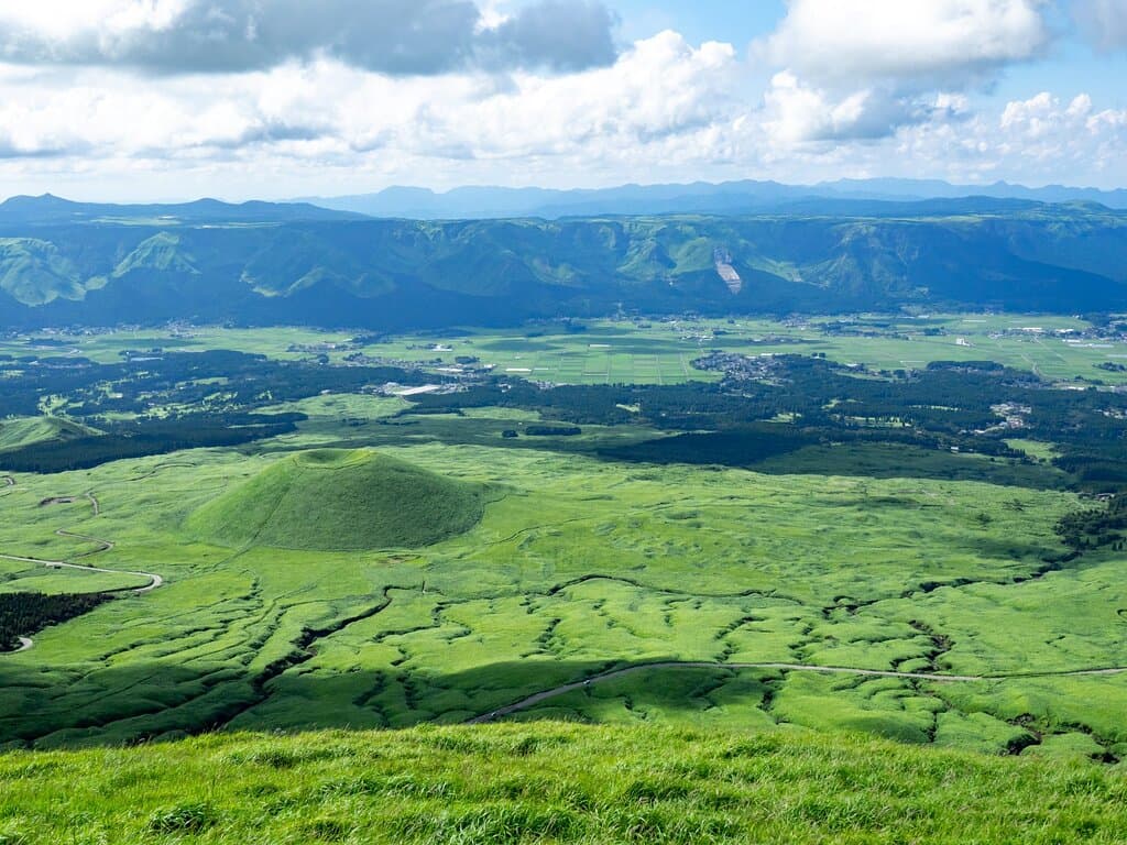 「米塚」という名前は、阿蘇神話の登場人物である健磐龍命（たけいわたつのみこと）が阿蘇中の米を集めて山にし、頂上を手ですくって人々に分け与えたという伝説に由来します。斜面は柔らかな草原に覆われているので、春から夏にかけては緑一色に染まり、美しい景色を見ることができます。