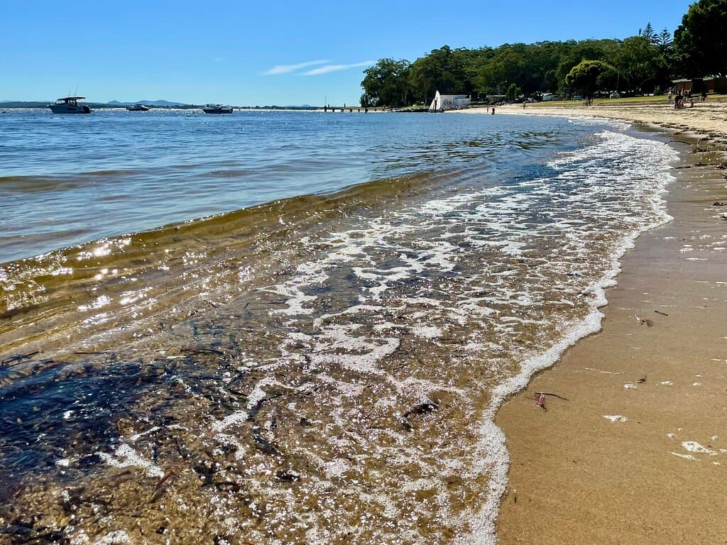 Little Beach is a small, calm beach on the bay with gently lapping water, a stretch of clean sand and a shady, grassy verge.