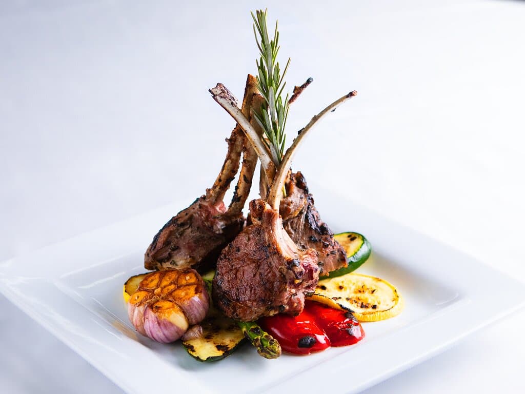 Grilled Lamb Chops | Grilled New Zealand lamb chops, grilled seasonal vegetables, herbed cous cous with a roasted garlic head.
