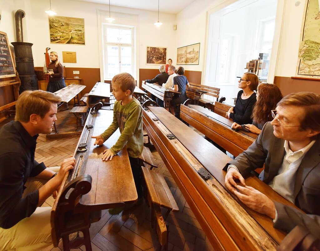 In einem der drei historischen Klassenzimmer aus 1900 können Besucherinnen und Besucher Platz nehmen in den alten, engen Schulbänken.