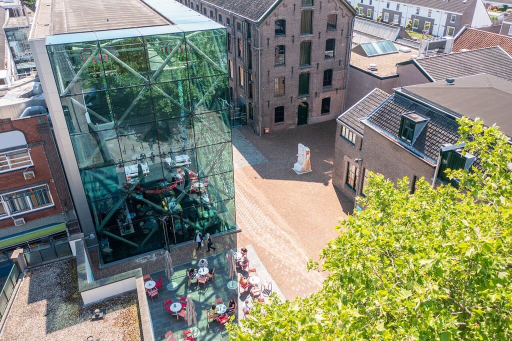 Het terrein van het TextielMuseum, hier zie je de voormalige textielfabriek en daarnaast het nieuwe glazen gebouw.