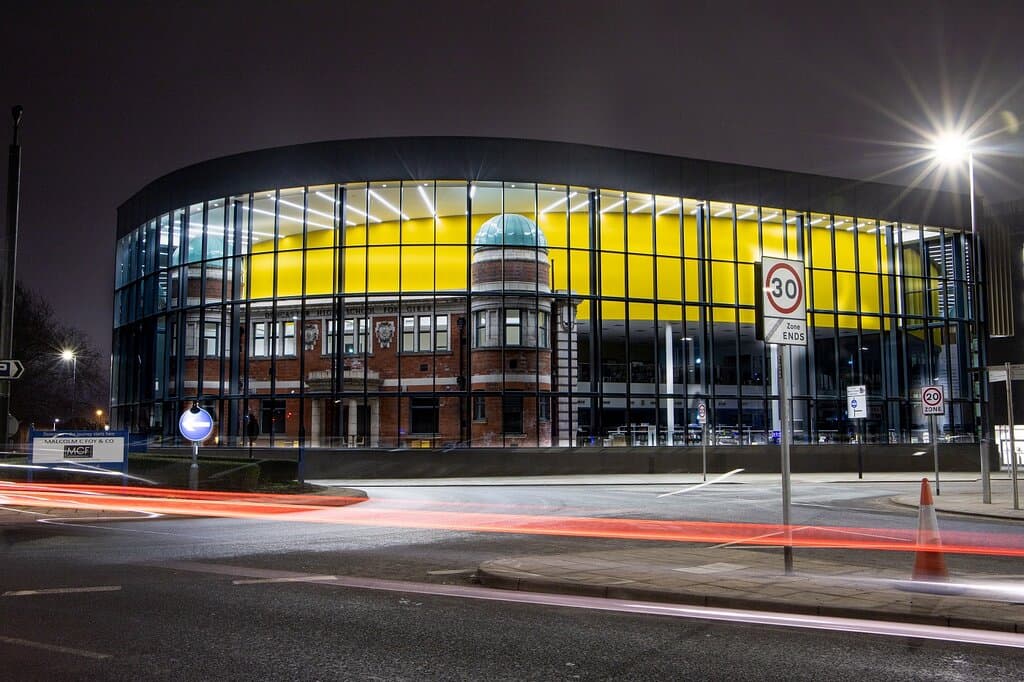 Façade of DGLAM lit up at night. 