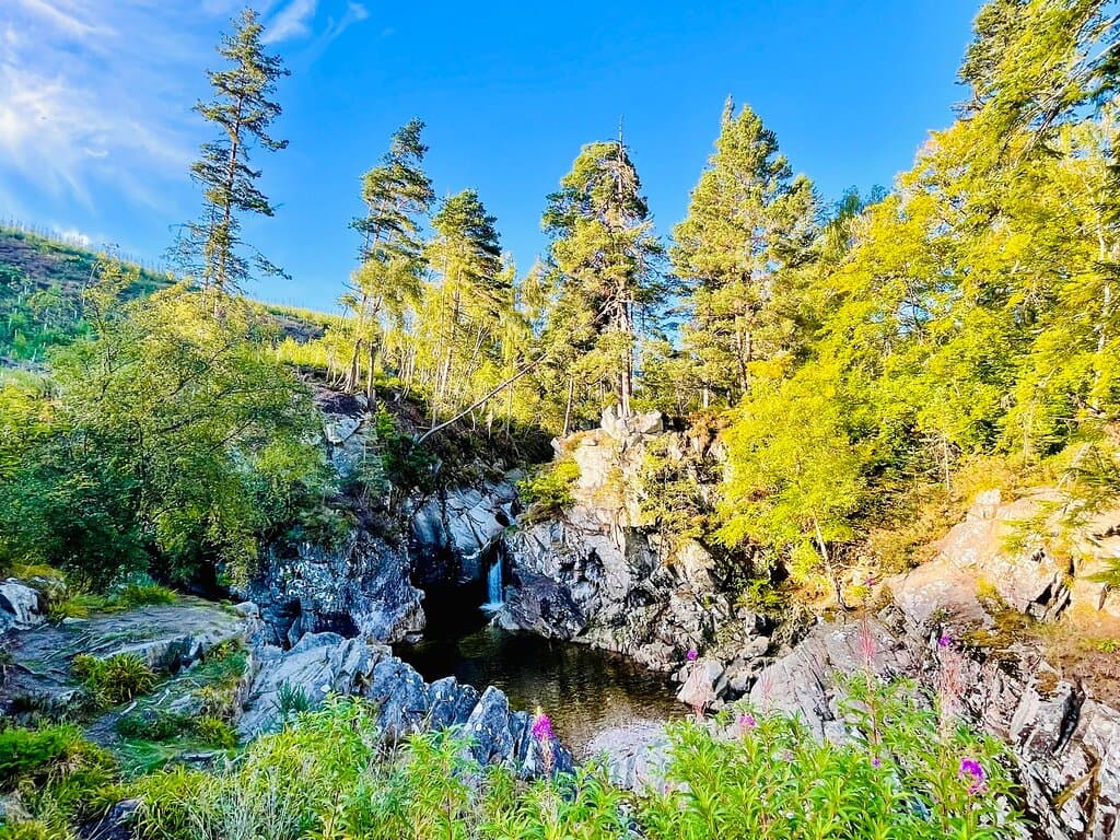 The water tumbles into deep black rocky pools.