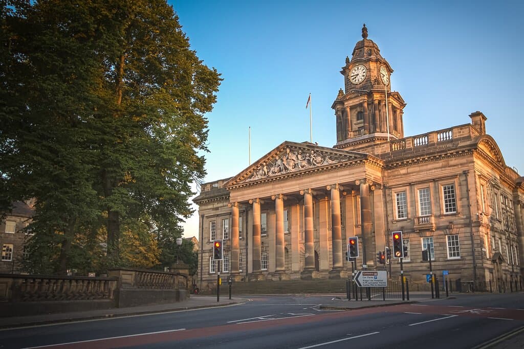 An exterior shot of Lancaster Town Hall, bathed in a warm sunlight. A tree can be seen in front of the building as can the traffic lights of a junction.