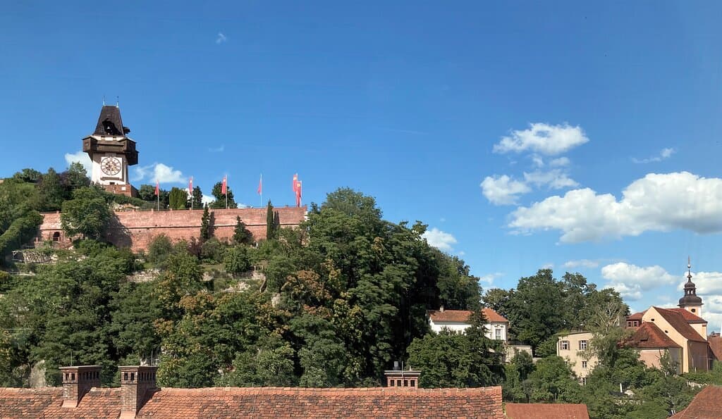 Schlossberg Graz mit Uhrturm und Stiegenkirche; rote Dächer von Graz als Unesco Kulturerbe