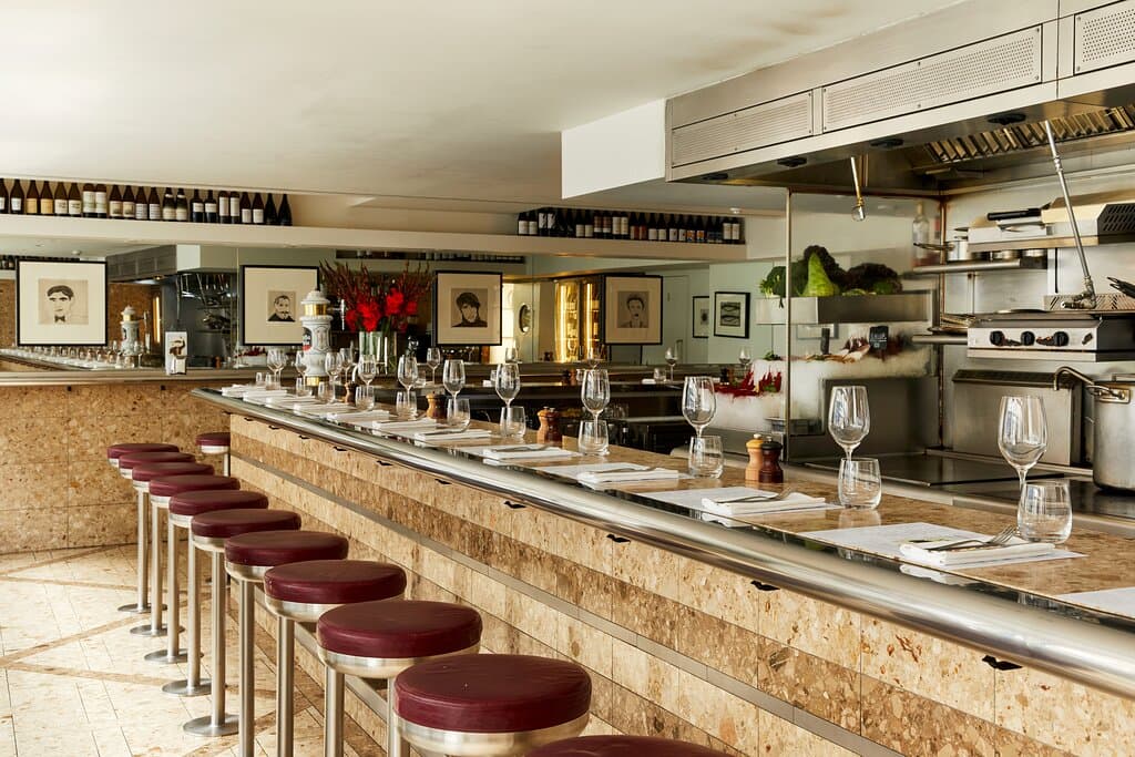 The original Barrafina, situated on Soho’s lively Dean Street, is the only location that doesn’t take reservations. The walk-in only restaurant operates on a first-come first served basis, with a standing bar where guests can enjoy drinks and para picar whilst waiting to be seated. Most guests sit at the L-shaped marble bar, offering a direct view of the chefs at work, while a few window seats allow diners to watch the world go by. The restaurant also has a covered, heated terrace at the front o