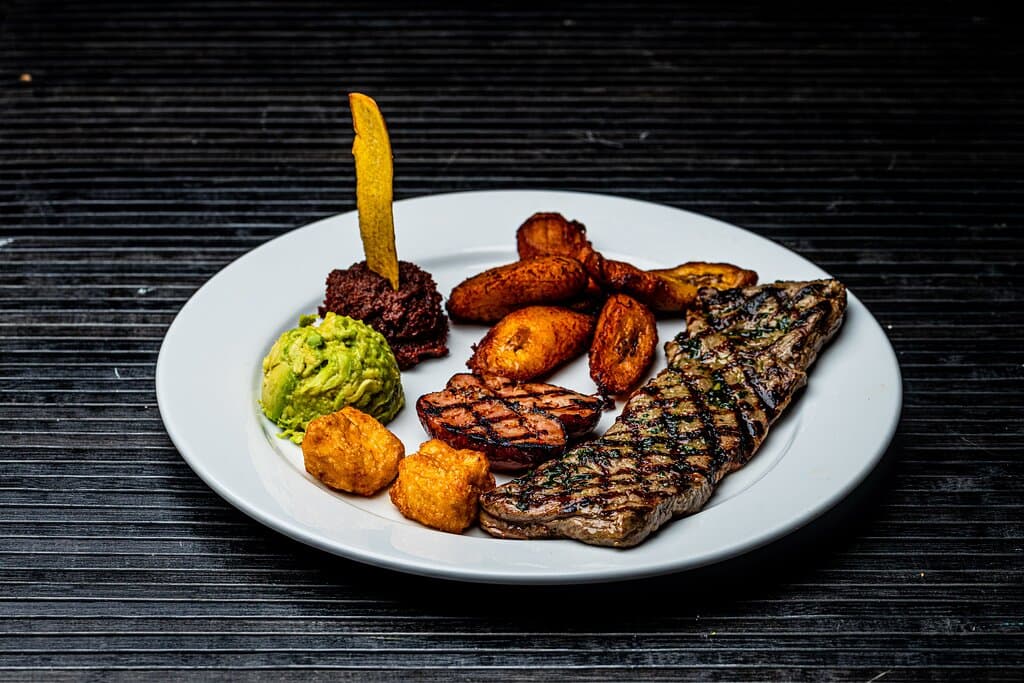 Exquisito churrasco de lomito de aguja, frijoles fritos Los Ranchos, queso frito, chorizo, maduros y guacamole.