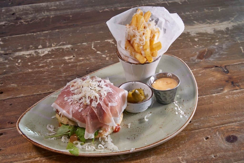 Parma burger with 150gr of rib eye meat, Brioche bun, prosciutto, brass tomato relish, rucola