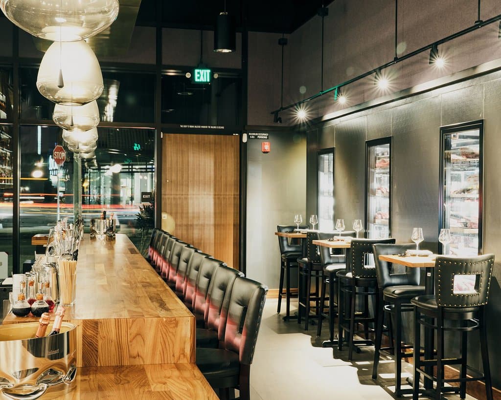 Our bar table seating has a view of our butcher shop through the wall