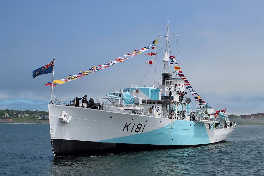 This is a photograph of HMCS Sackville fully dressed for ceremonial purposes. She is in the harbour, approaching Sackville landing.