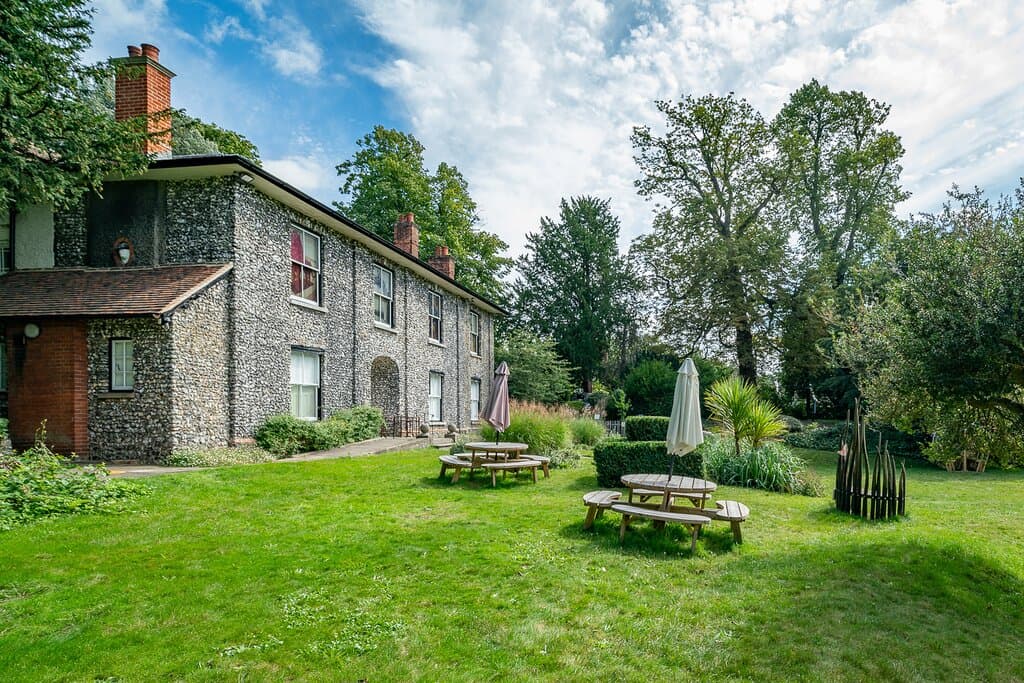 A Grade II listed flint-faced building in an acre of gardens.