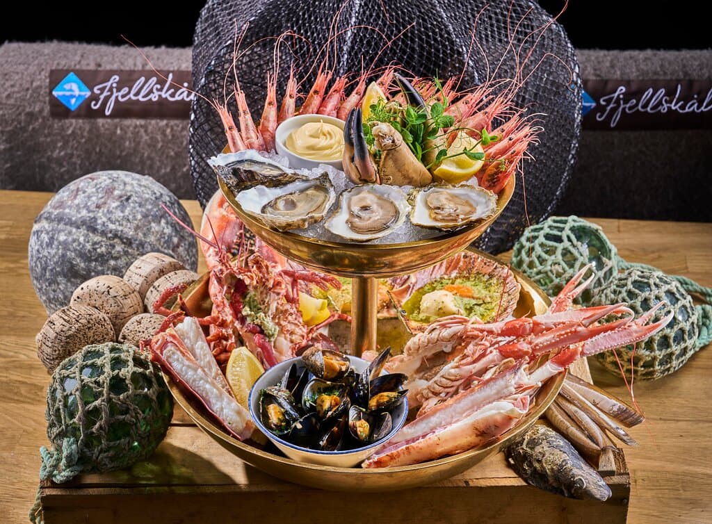 Fjellskål’s “Luxury” Shellfish Symphony. Our signature shellfish tower, designed for sharing: cold fresh shrimp (boiled and chilled, with shell on), cold stone crab claws, live king scallops (gratinated with chervil-tarragon butter, garlic, and aged parmesan), plus live king crab, langoustines, and lobster – all prepared to your preference: naturally steamed or grilled with garlic oil or chervil-tarragon butter.